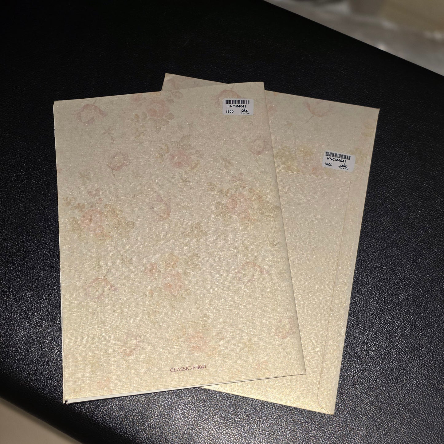 Three vintage-style floral patterned notebooks or booklets with a linen-like texture, stacked on a dark textured surface.