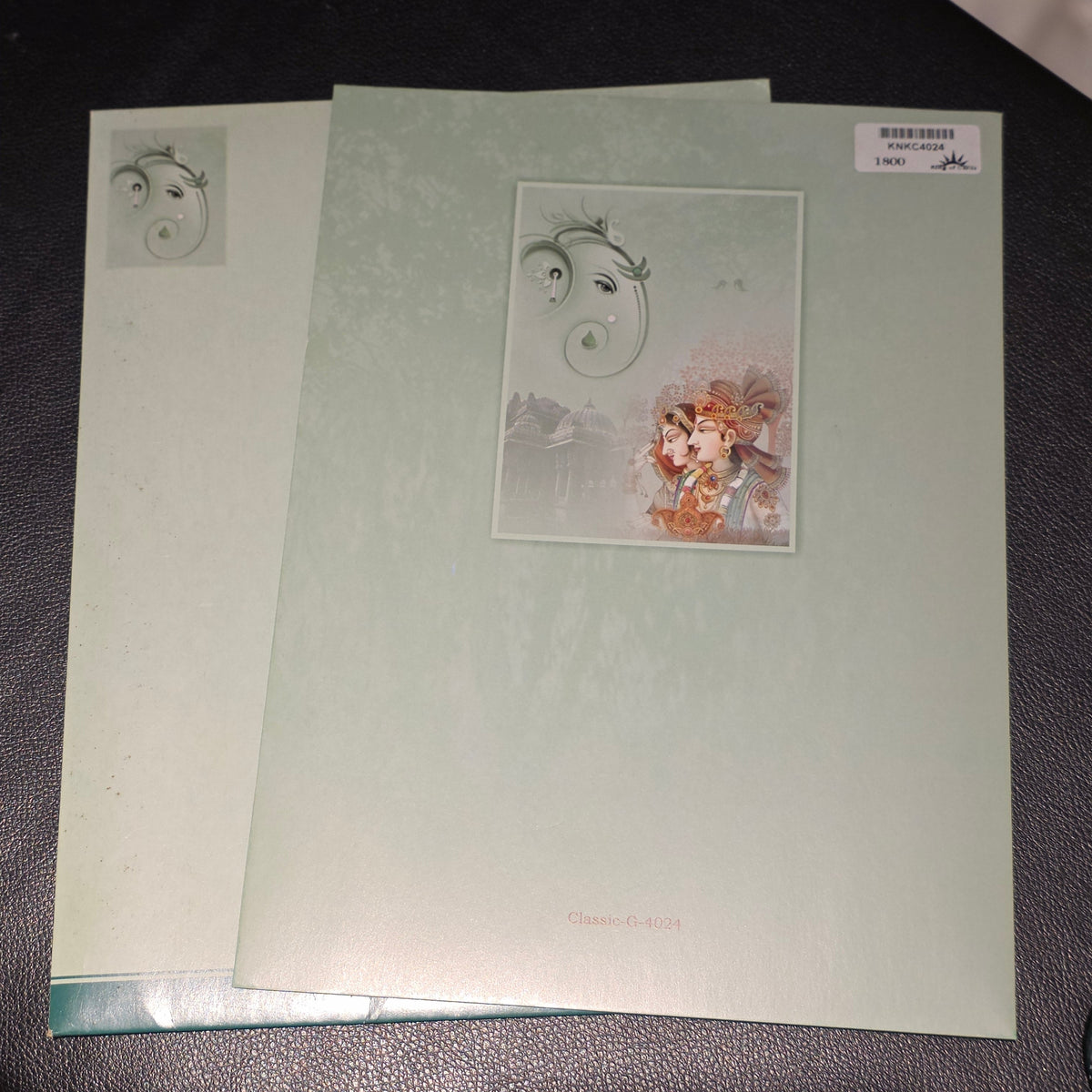 A set of light sage green art cards or mini albums with delicate illustrations, displayed on a dark textured surface.