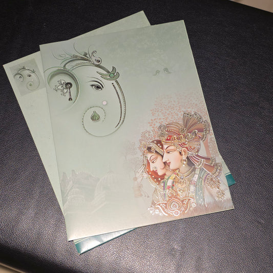A stack of decorative paper envelopes or cards with a pale green background, featuring a stylized elephant head illustration and a traditional illustrated couple on the front, placed on a dark textured surface.