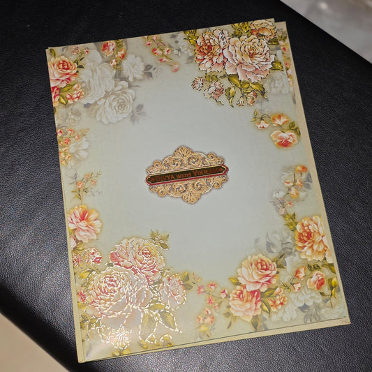 A rectangular decorative card or envelope with a vintage floral border and a central ornate label, photographed on a dark textured surface.