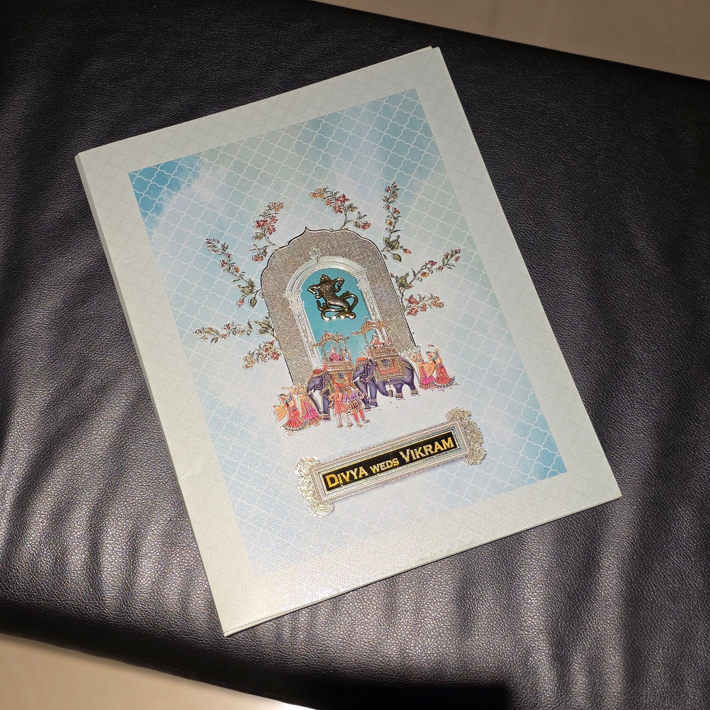 A printed card or art print titled 'DIVA with VIRMAN' featuring a stylized illustration of a horse and rider under a decorative arch, placed on a black leather surface.