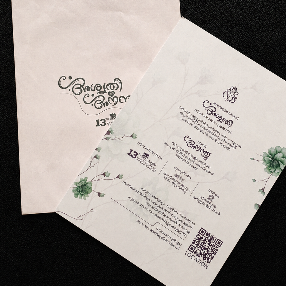 Two white printed invitation cards and envelopes with green floral illustrations and black text, placed on a black fabric background.