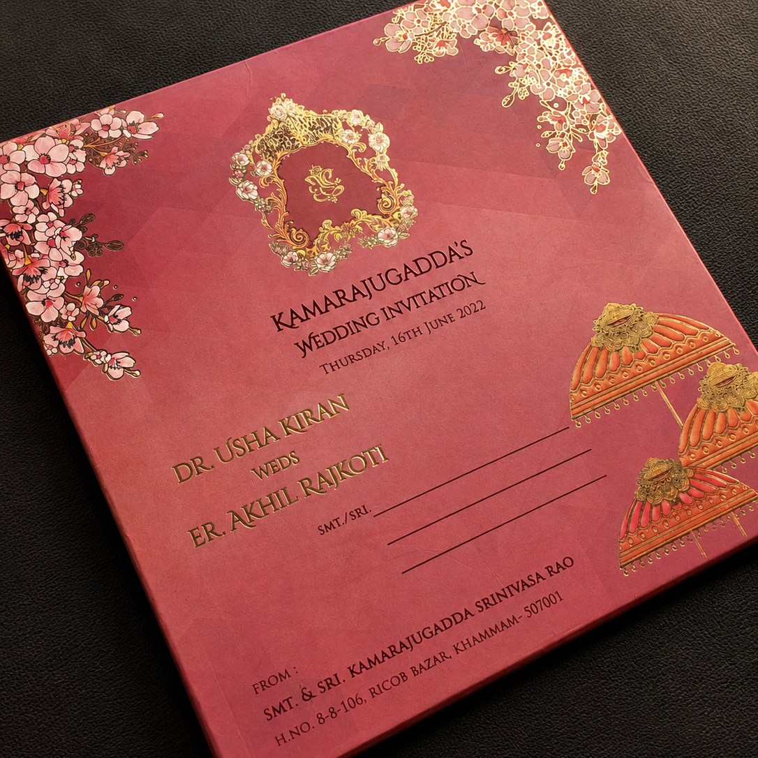 A deep pink and gold traditional Indian wedding invitation card featuring floral designs, ornate gold foil motifs, and text for 'Kamaratujaddas Wedding Invitation'.